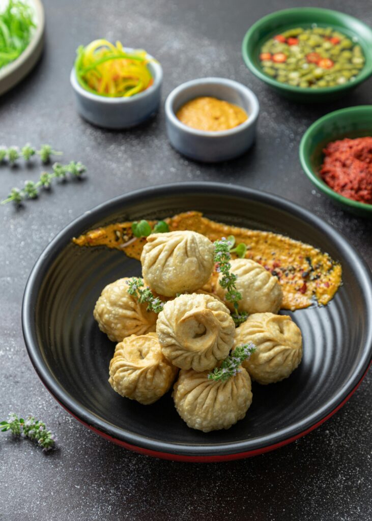 A bowl of fried dumplings served with garnishes and assorted dips, showcasing traditional cuisine.